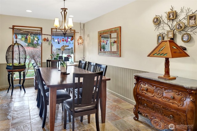 dining room featuring recessed lighting, a wainscoted wall, a notable chandelier, and stone finish floor