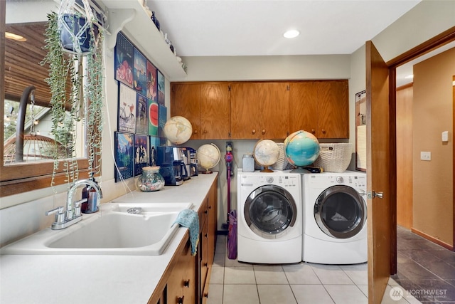 laundry room featuring washing machine and clothes dryer, cabinet space, light tile patterned flooring, and a sink