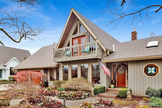 view of front of house with a chimney, a shingled roof, and a balcony