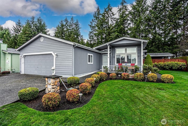 view of front of property with a front yard, fence, driveway, an attached garage, and covered porch