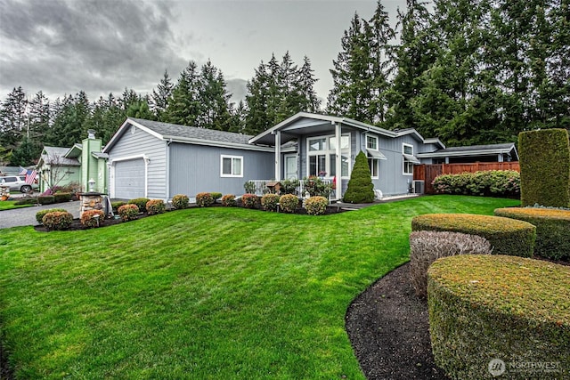 view of front of home with a front yard, central AC unit, fence, driveway, and a garage