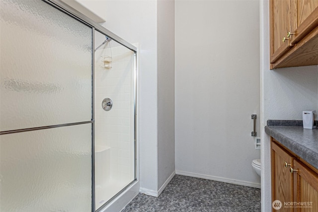 full bathroom with baseboards, toilet, vanity, and a shower stall