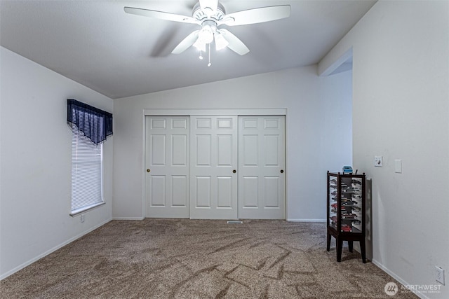 unfurnished bedroom with a closet, carpet floors, baseboards, ceiling fan, and vaulted ceiling