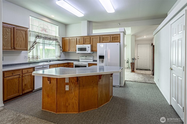 kitchen featuring a sink, white appliances, brown cabinets, and a center island