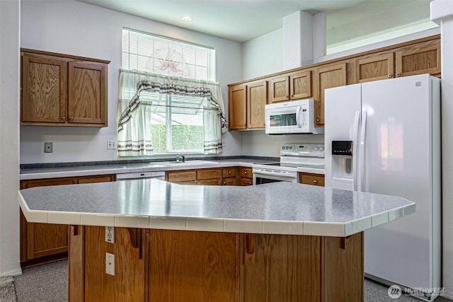 kitchen featuring a kitchen island, light countertops, brown cabinetry, white appliances, and a sink