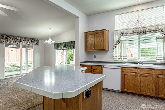 kitchen featuring dishwasher, vaulted ceiling, ceiling fan with notable chandelier, brown cabinetry, and a sink