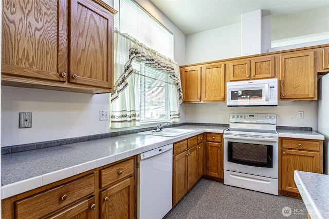 kitchen featuring white appliances, light countertops, brown cabinets, and a sink