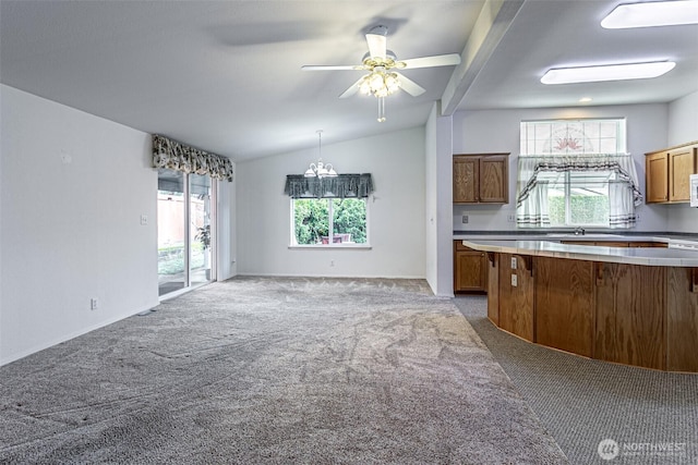 kitchen featuring lofted ceiling, a healthy amount of sunlight, brown cabinetry, and light carpet