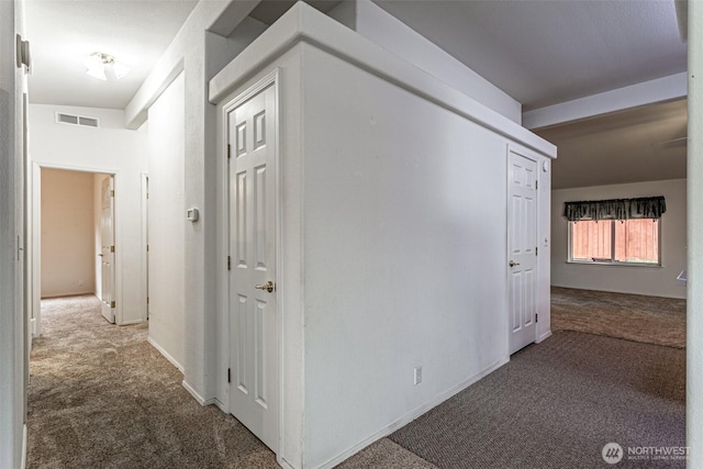 hallway with visible vents, carpet floors, and baseboards