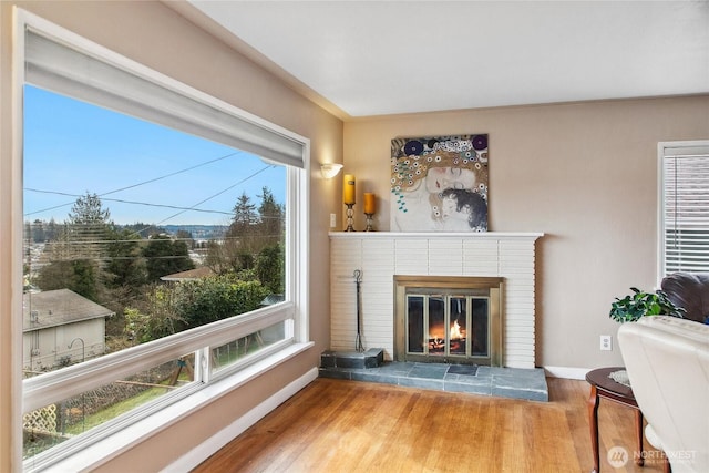 living area with a fireplace, wood finished floors, and baseboards