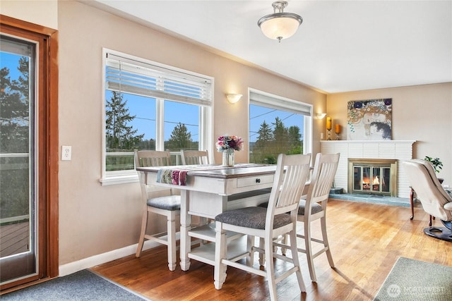 dining area with a brick fireplace, wood finished floors, and baseboards