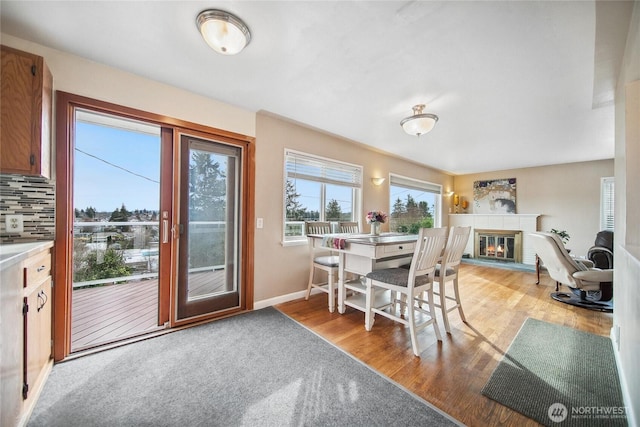 dining area featuring a brick fireplace, light wood-type flooring, and baseboards