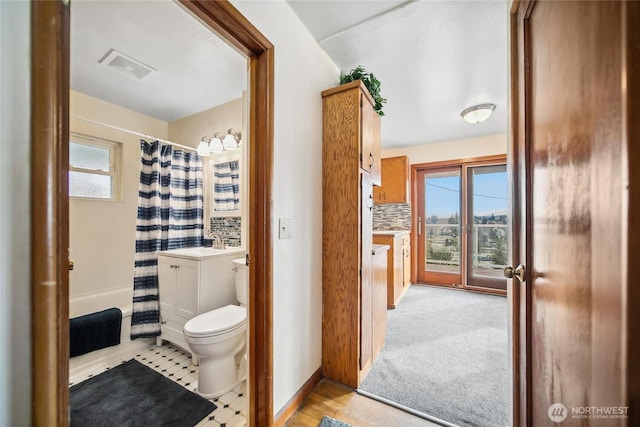 bathroom featuring visible vents, toilet, decorative backsplash, baseboards, and vanity