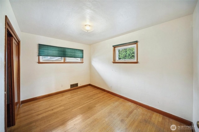 unfurnished bedroom with light wood-style flooring, baseboards, visible vents, and a textured ceiling