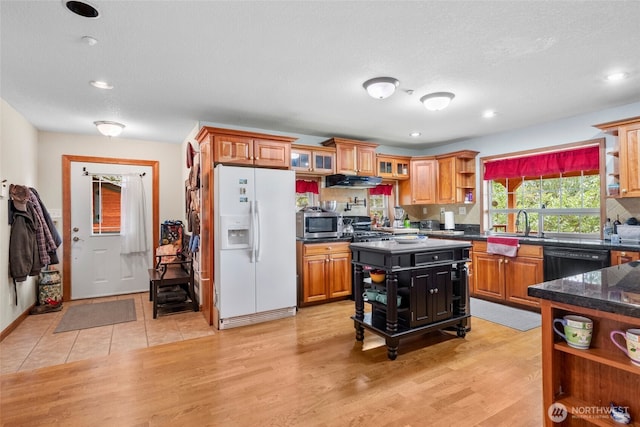 kitchen featuring open shelves, light wood-style flooring, white refrigerator with ice dispenser, and a sink