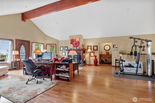 office with beamed ceiling, a fireplace with raised hearth, light wood-style floors, and high vaulted ceiling