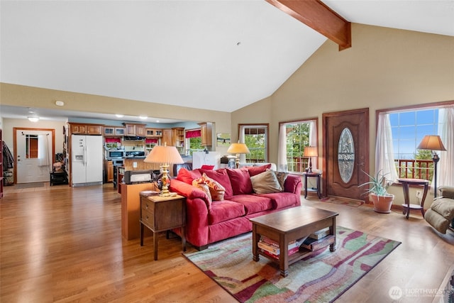 living room featuring light wood-type flooring, beam ceiling, and high vaulted ceiling