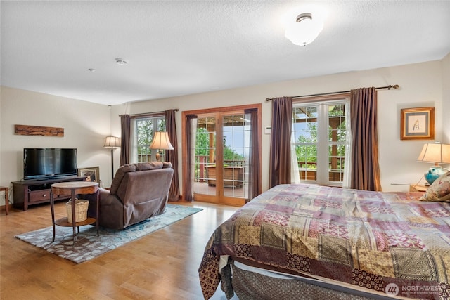 bedroom with access to outside, light wood-style flooring, french doors, and a textured ceiling