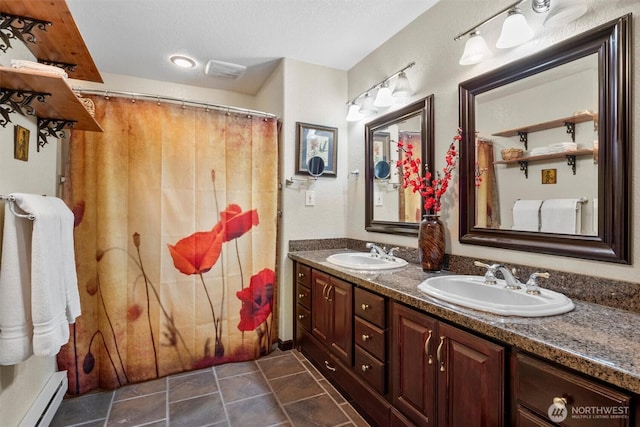 bathroom with double vanity, baseboard heating, a textured ceiling, and a sink