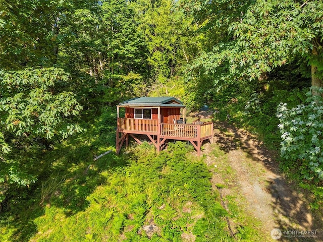 exterior space with a wooded view, dirt driveway, and a wooden deck