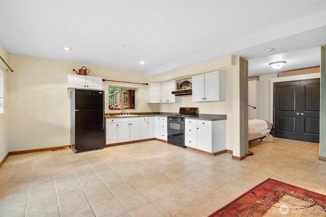 kitchen with dark countertops, white cabinets, black appliances, and a sink