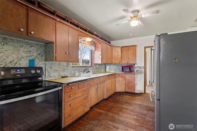 kitchen featuring freestanding refrigerator, a sink, dark wood-type flooring, black range with electric cooktop, and backsplash