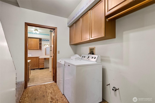 washroom featuring cabinet space, light wood-style flooring, and washer and clothes dryer