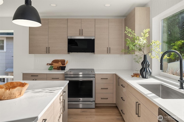 kitchen with light brown cabinetry, recessed lighting, appliances with stainless steel finishes, light wood-style floors, and a sink