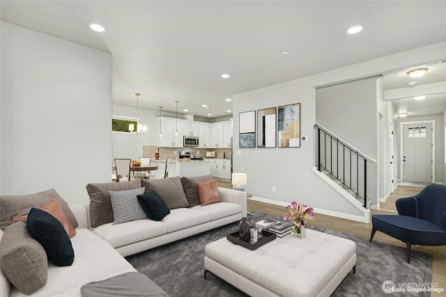 living room with stairway, a healthy amount of sunlight, baseboards, recessed lighting, and light wood-type flooring