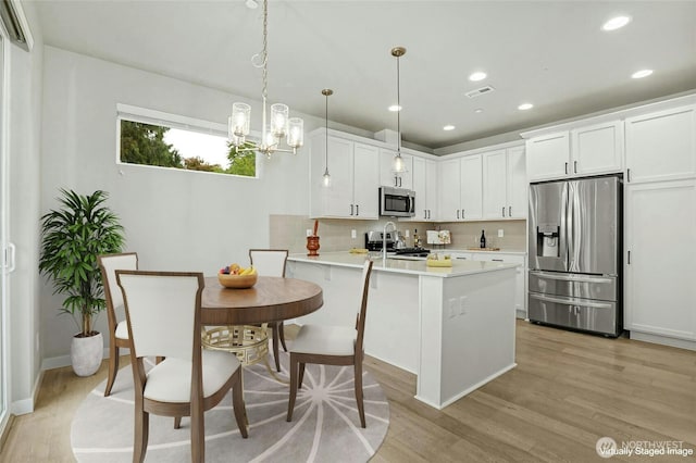 kitchen featuring visible vents, light wood-style flooring, backsplash, stainless steel appliances, and a peninsula