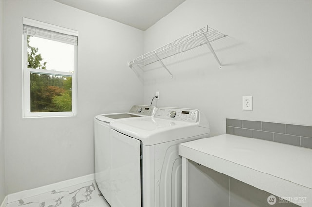 clothes washing area featuring washing machine and clothes dryer, laundry area, marble finish floor, and baseboards