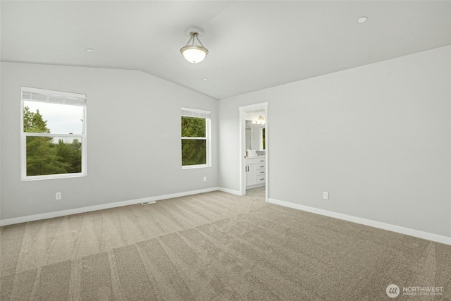 carpeted empty room featuring lofted ceiling and baseboards