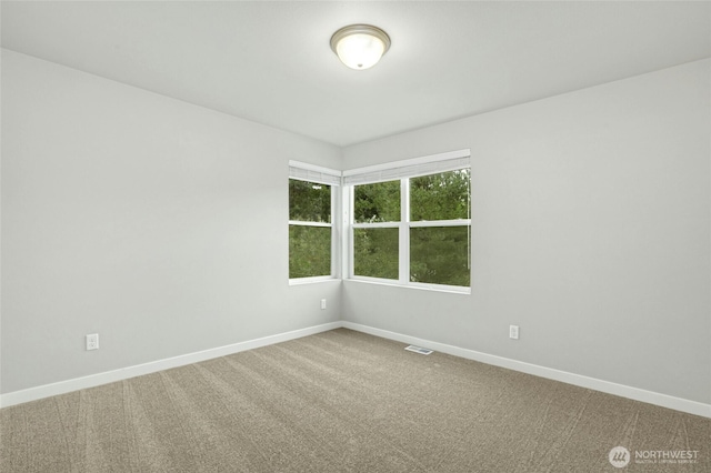 unfurnished room with carpet flooring, visible vents, and baseboards