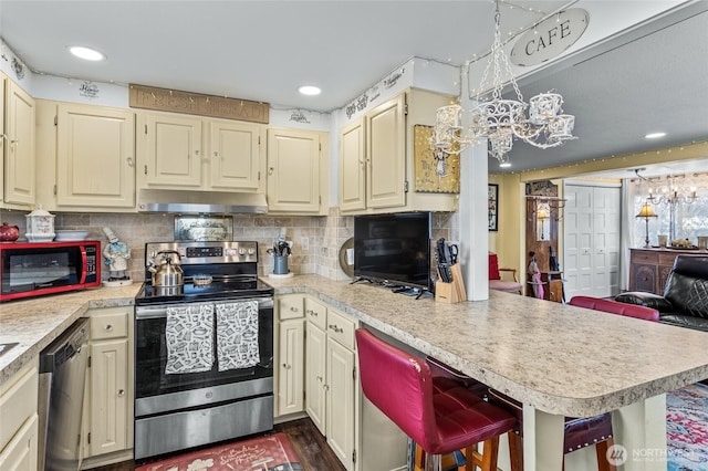 kitchen featuring tasteful backsplash, a peninsula, appliances with stainless steel finishes, exhaust hood, and light countertops