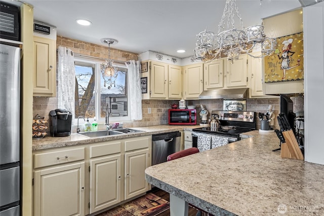 kitchen featuring under cabinet range hood, light countertops, appliances with stainless steel finishes, an inviting chandelier, and a sink