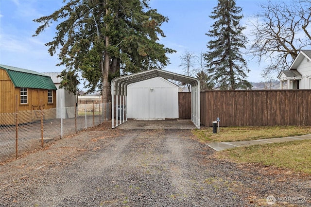 garage with a detached carport, driveway, and fence