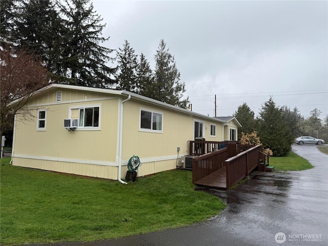 view of property exterior featuring driveway, a wooden deck, and a yard