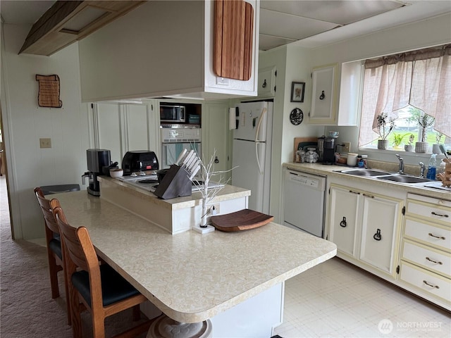 kitchen with a center island, light floors, light countertops, white appliances, and a sink