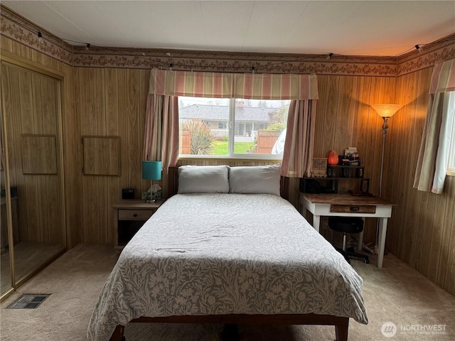 bedroom featuring light carpet, visible vents, and wooden walls