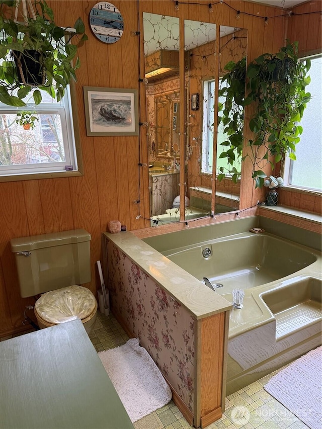 bathroom featuring tile patterned floors, a garden tub, toilet, and wood walls