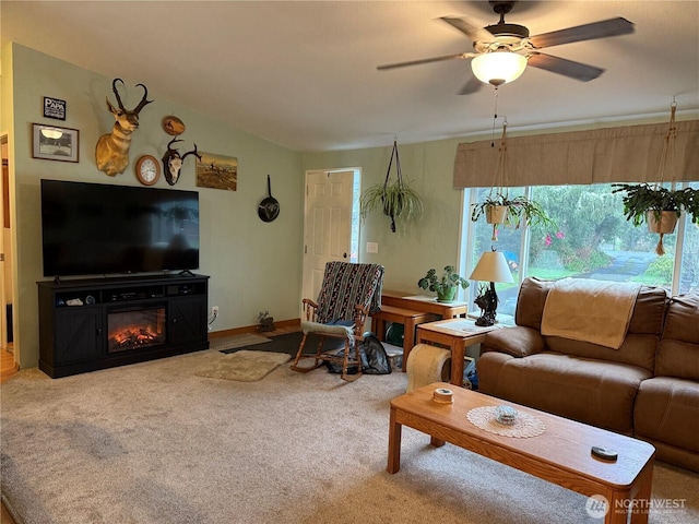 living room with baseboards, ceiling fan, vaulted ceiling, a glass covered fireplace, and carpet flooring