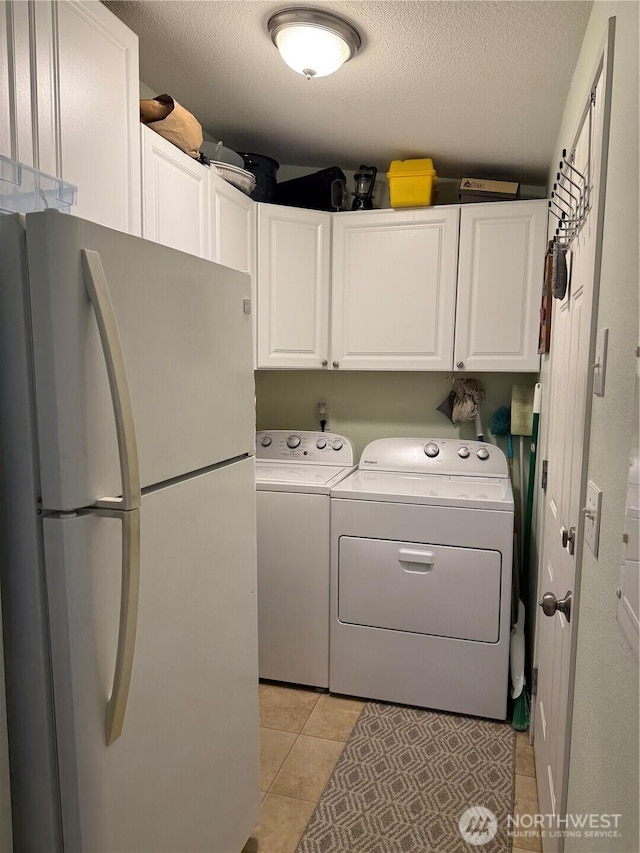 laundry room featuring light tile patterned floors, independent washer and dryer, a textured ceiling, and cabinet space