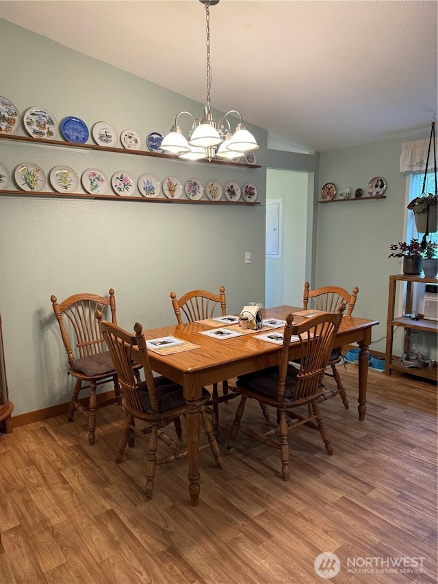 dining room with baseboards, lofted ceiling, an inviting chandelier, and light wood-style flooring