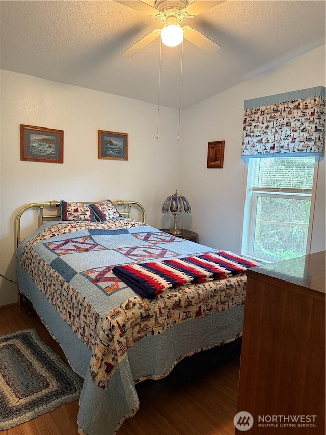 bedroom with a ceiling fan, wood finished floors, and a textured ceiling