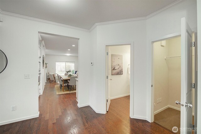 corridor with crown molding, dark wood-type flooring, and baseboards