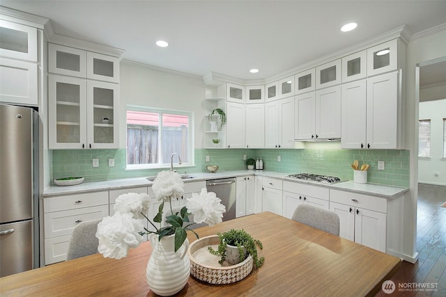 kitchen featuring light countertops, ornamental molding, hardwood / wood-style floors, appliances with stainless steel finishes, and a sink