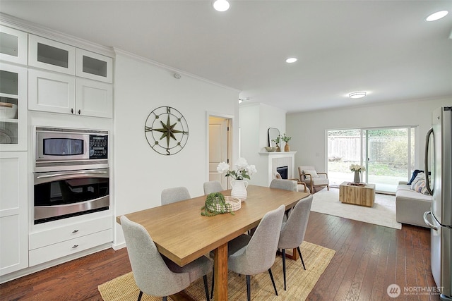 dining area with recessed lighting, a fireplace, dark wood finished floors, and crown molding