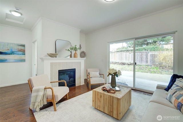 living room with visible vents, light wood-style floors, crown molding, and a tile fireplace