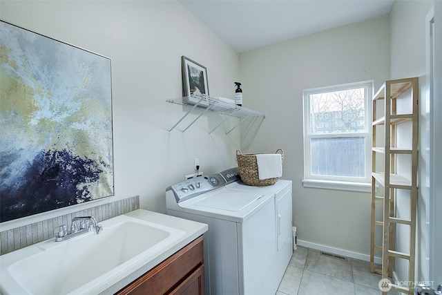 clothes washing area with visible vents, baseboards, washing machine and dryer, light tile patterned flooring, and a sink