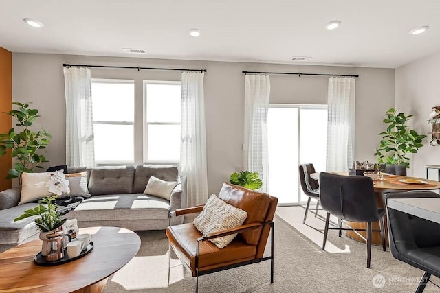 living area featuring light carpet, visible vents, and recessed lighting